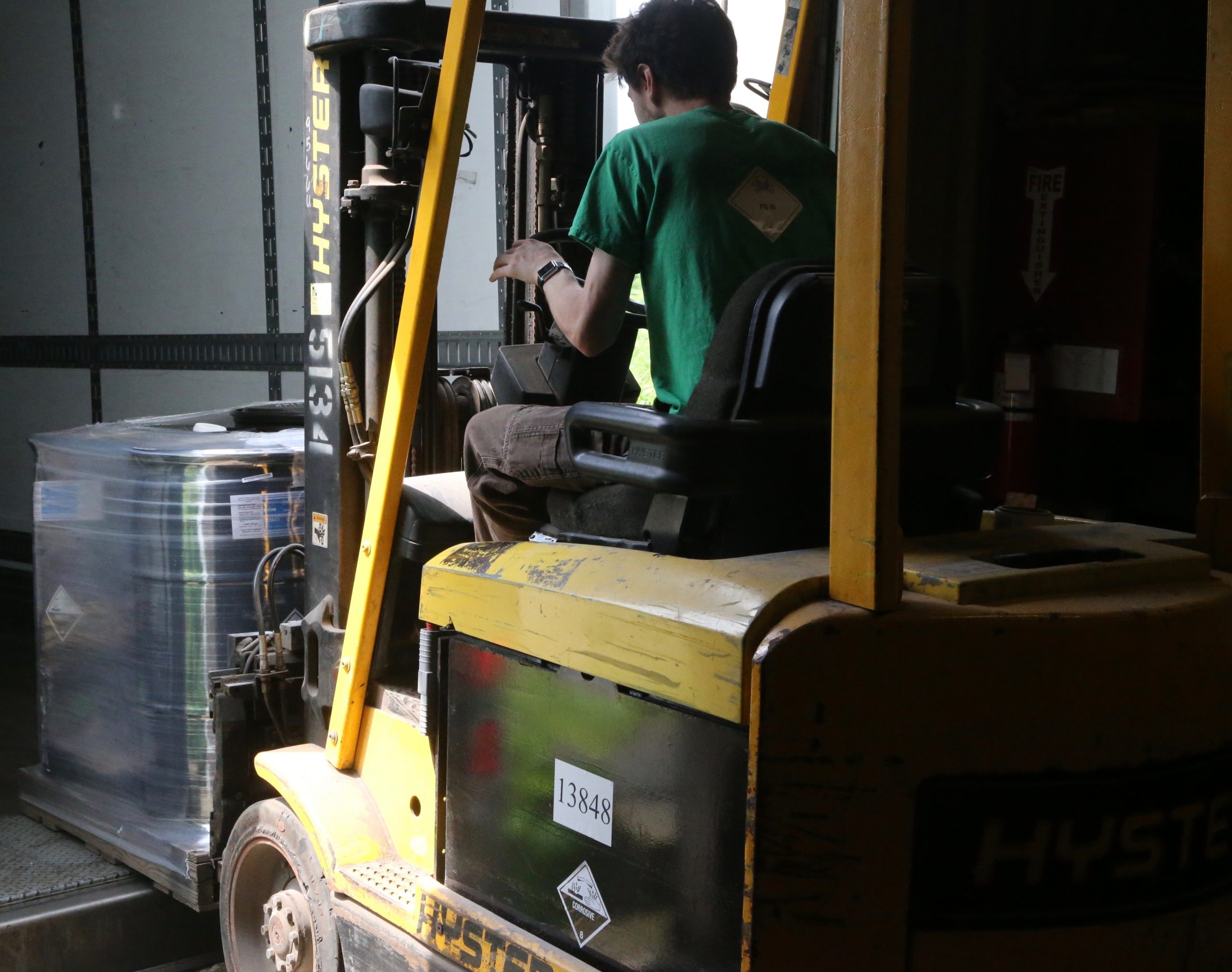 Warehouse worker lifts containers of product Warehouse worker lifts containers of product