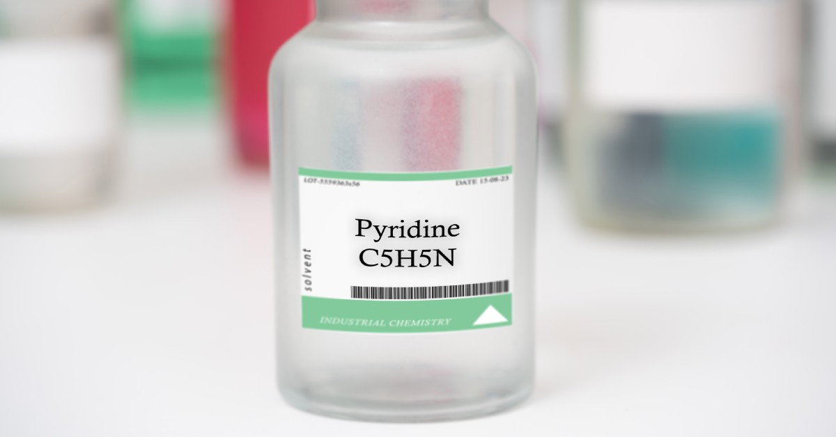 Focus on a clear bottle labeled 'Pyridine C5H5N.' Several other chemical bottles are blurred in the background.