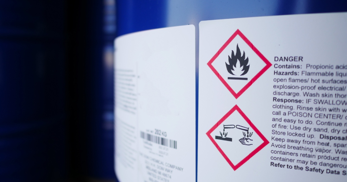 A chemical storage tank with a label noting the dangers associated with the chemical. The chemical storage tank is blue.