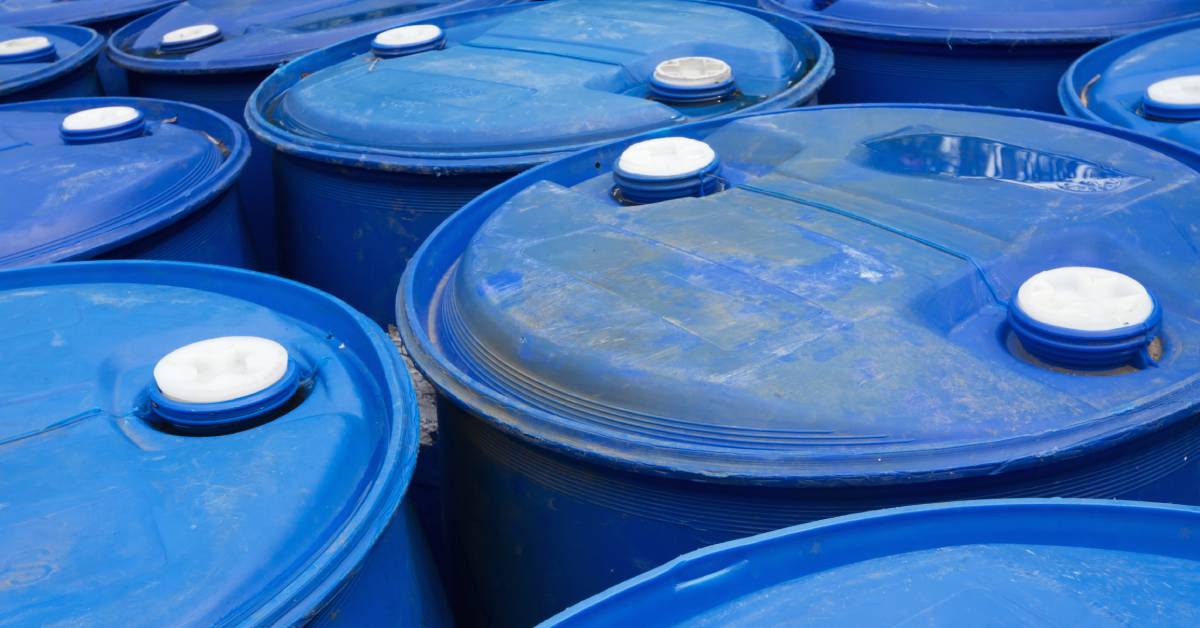 A close-up of a collection of blue polyethylene drums. The tops of the drums have small white lids attached.