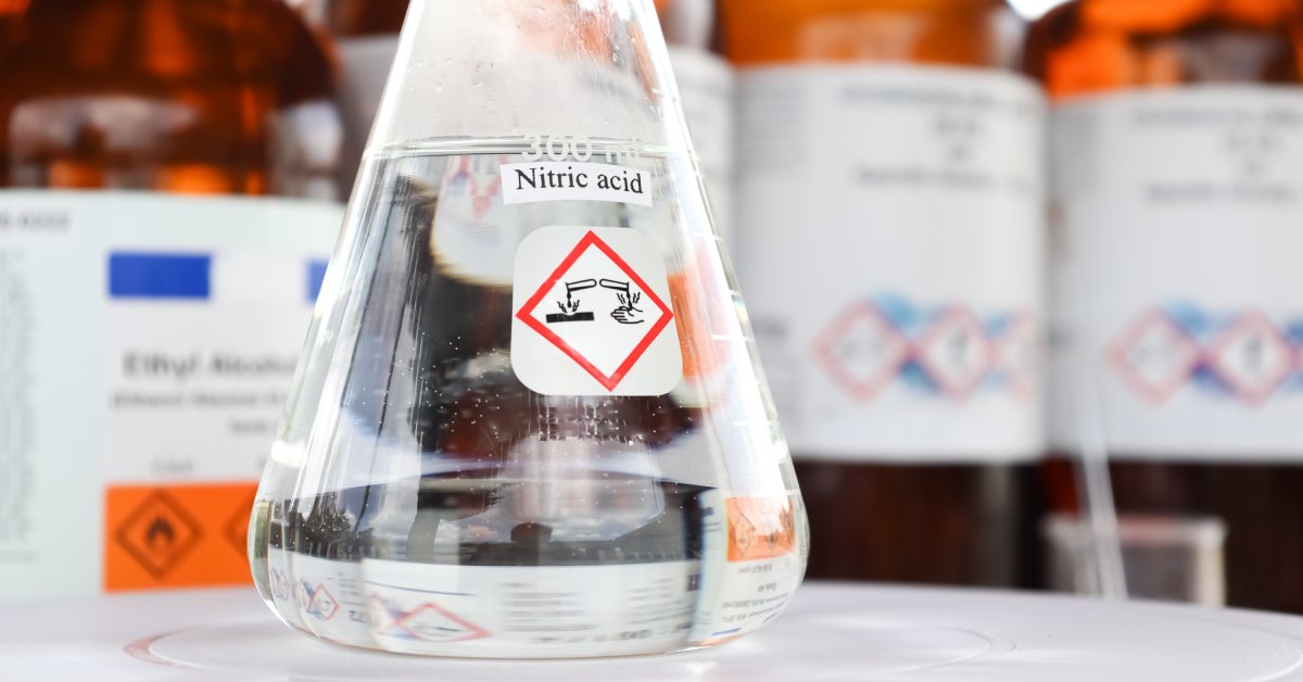 A laboratory glass with nitric acid inside of it. The glass has a nitric acid label on it and it's filled up to 300 ml.
