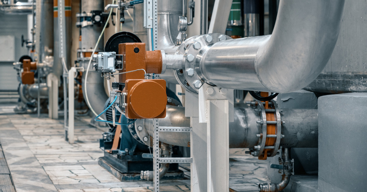 A room in a pipeline facility filled with metal pipes and other components, including various valves and meters.